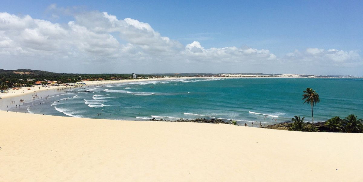 Praia de Genipabu no Rio Grande do Norte, com dunas de areia branca, mar azul e buggy sobre as dunas